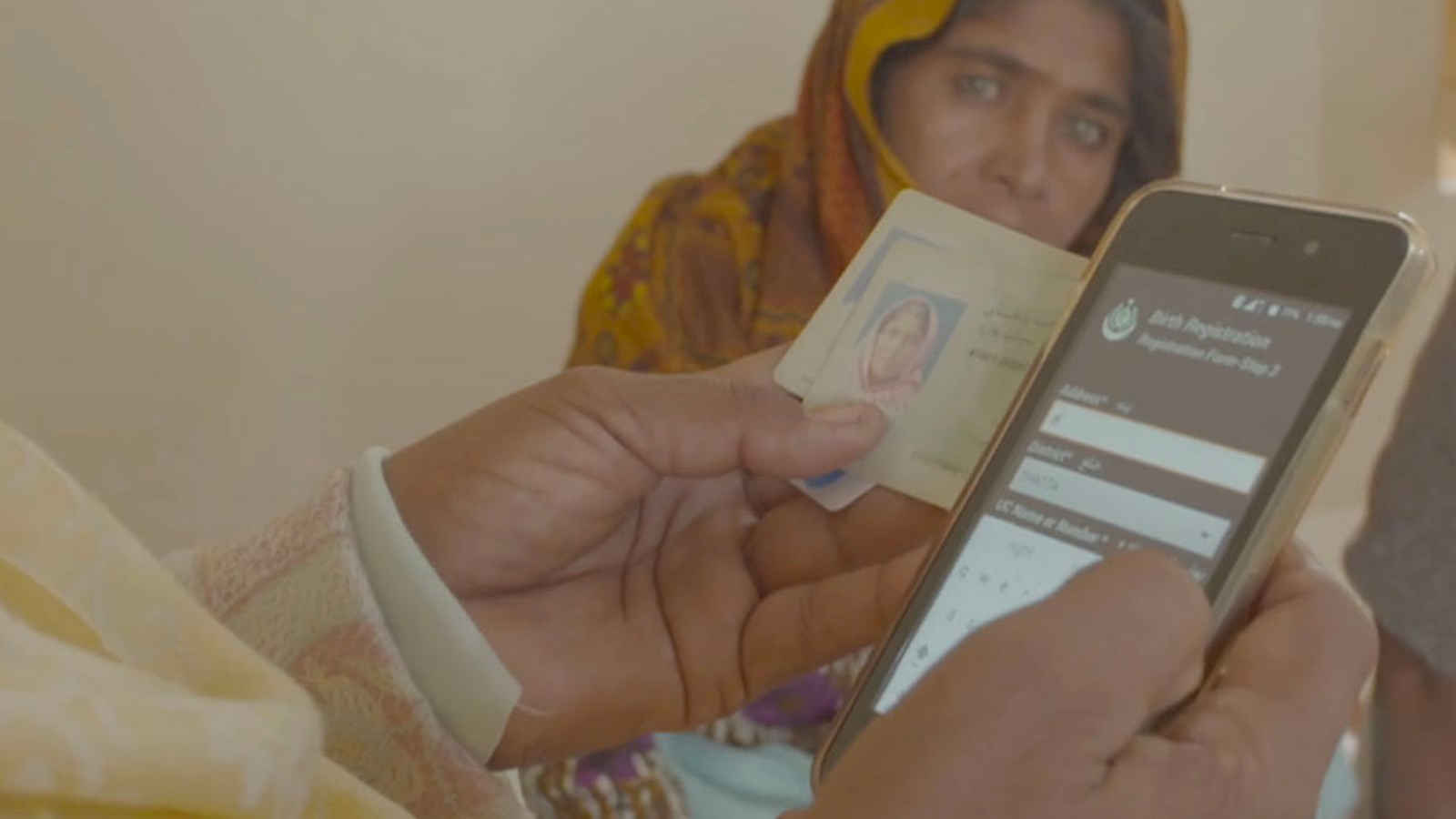 Someone filling out form on mobile phone with woman's face in the background